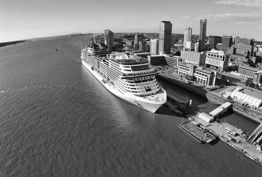 Black-and-white aerial view of a large cruise ship moored along a city waterfront